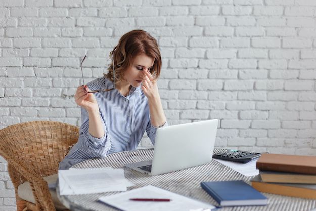 young woman aspiring author having a difficult time in front of her laptop