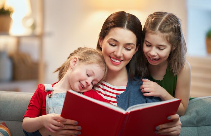 mother reading a book to her two daughters